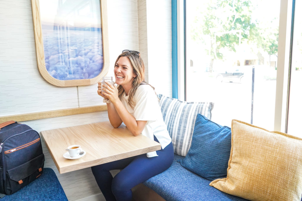 customer smiling holding coffee at window seat in Dallas