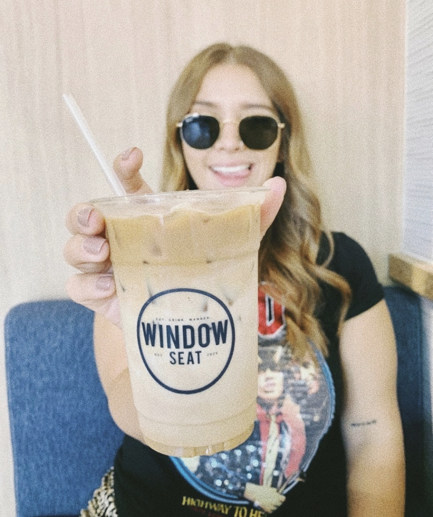 Woman holding coffee cup with Window Seat logo