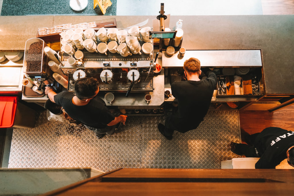Overhead look at baristas working in coffee shop behind bar