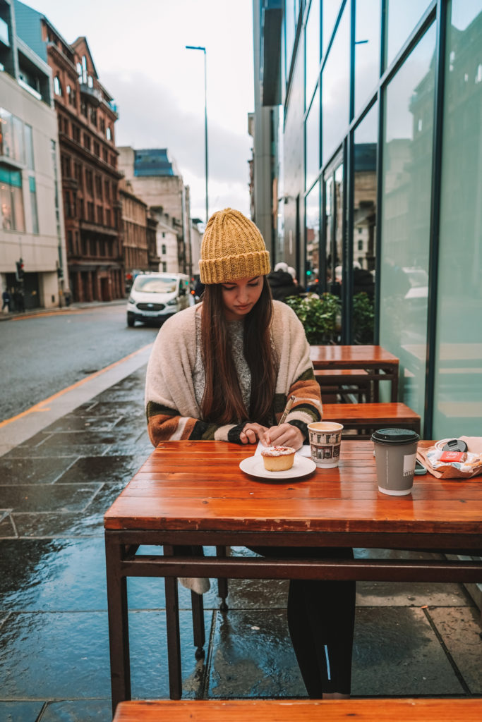 woman sitting outdoors at a cafe table with coffee