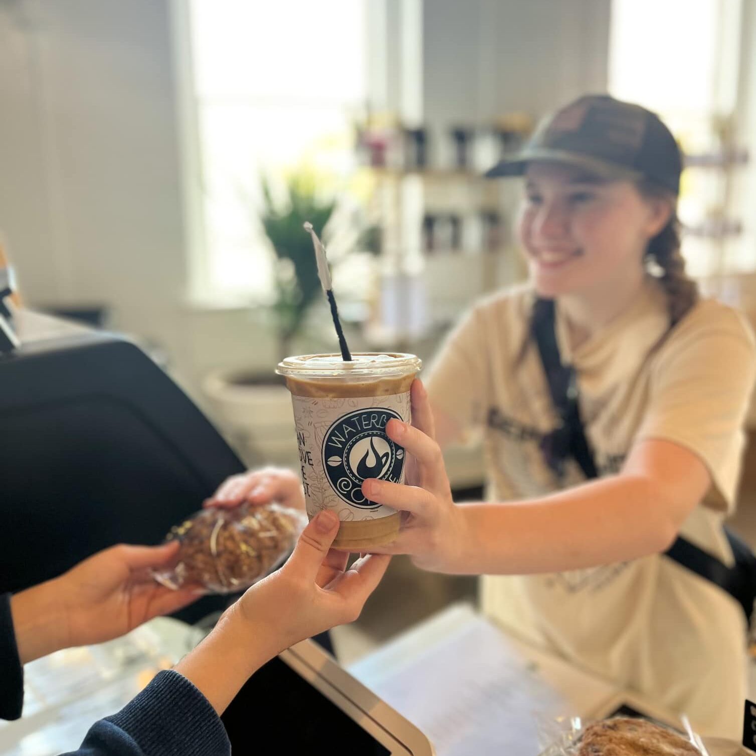 A barista passes a drink to a customer.