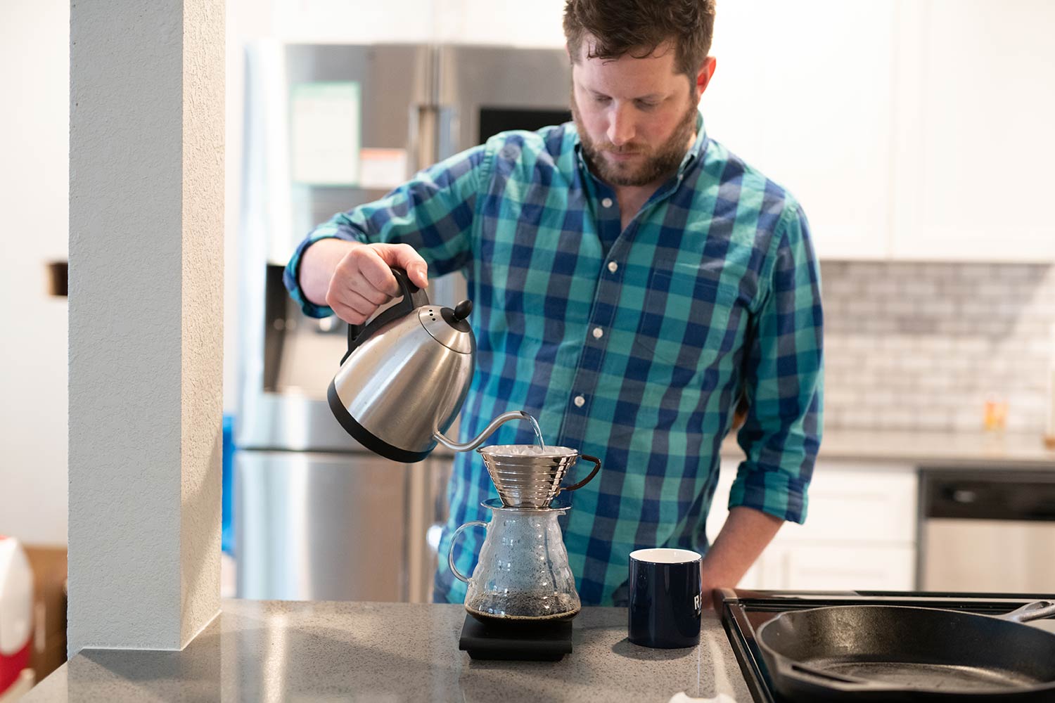 Home coffee enthusiast using a kalita wave to make a pour-over coffee