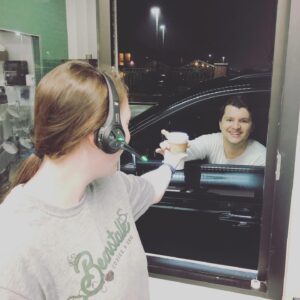drive-thru coffee shop barista handing customer a coffee through the window