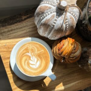 A fall coffee drink sits nexts to pumpkins.