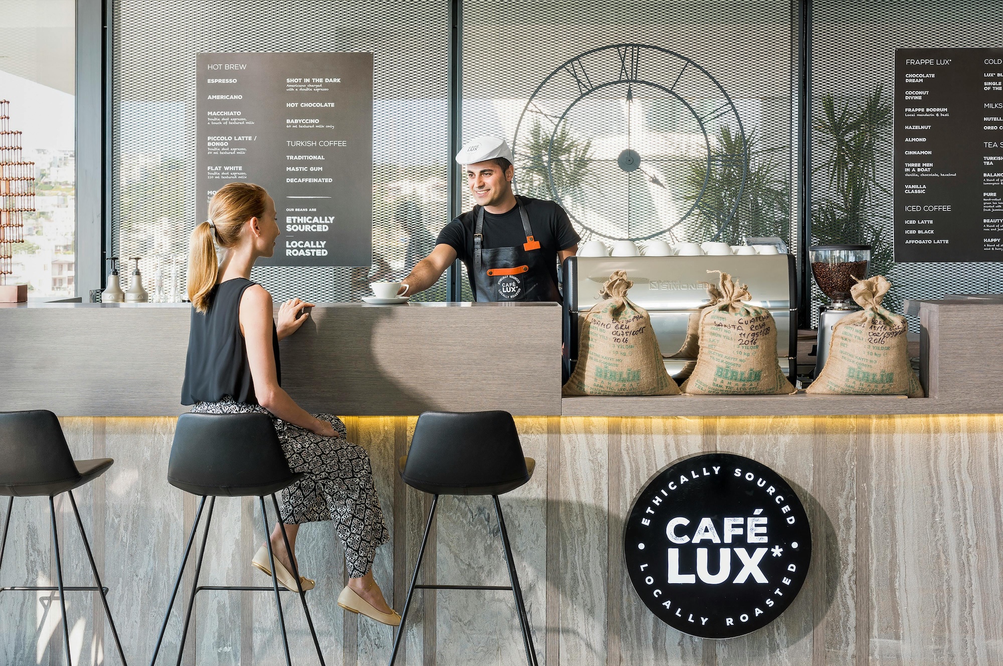 A barista hands a customer their drink.