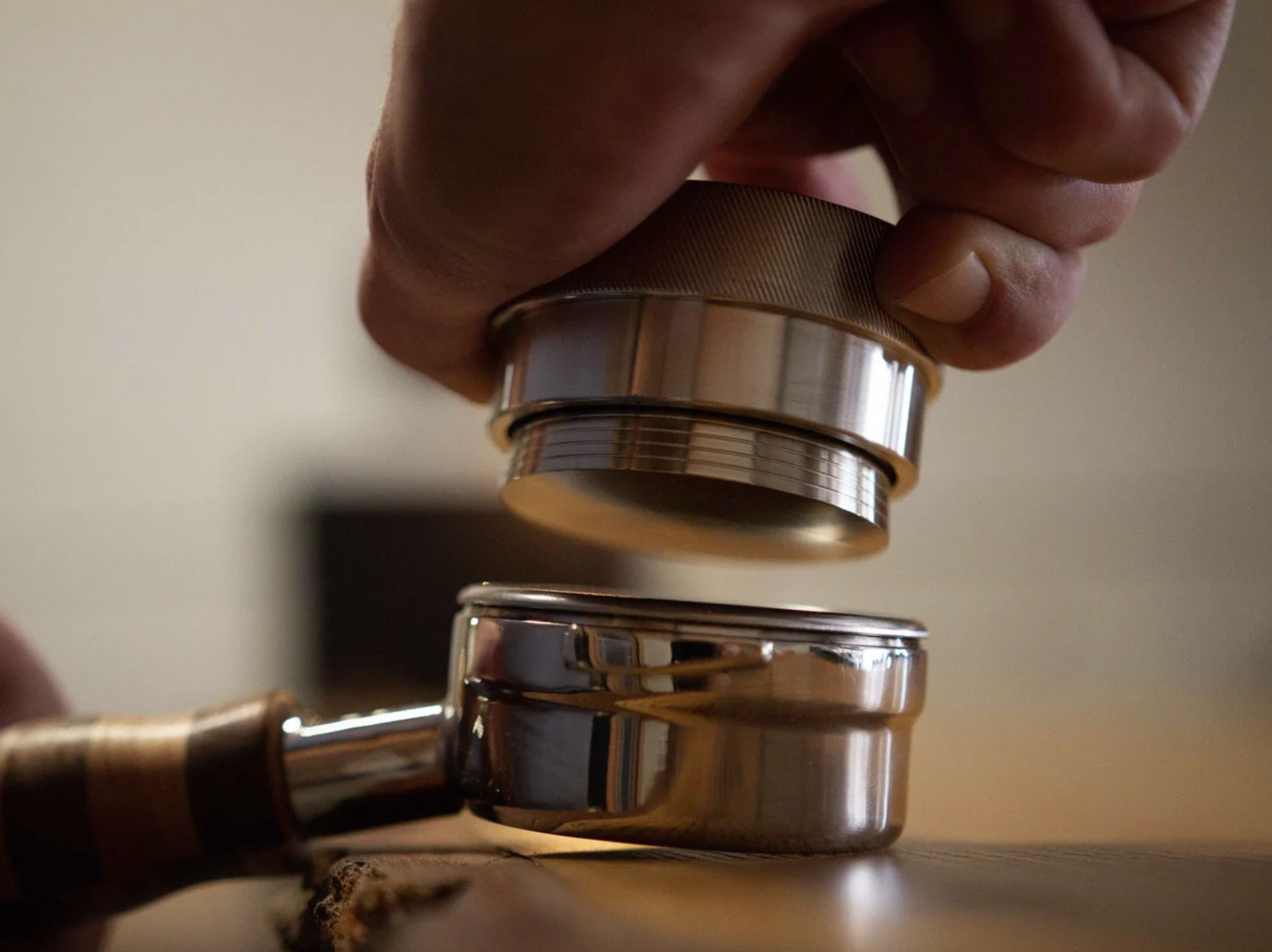 A person uses a tamper for an espresso pull.