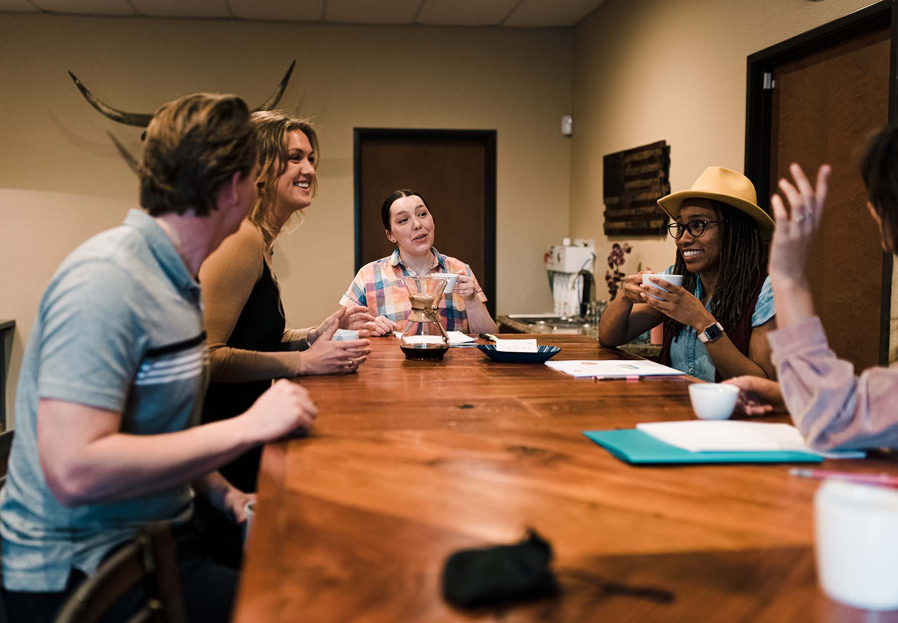 People laugh around a coffee shop table.