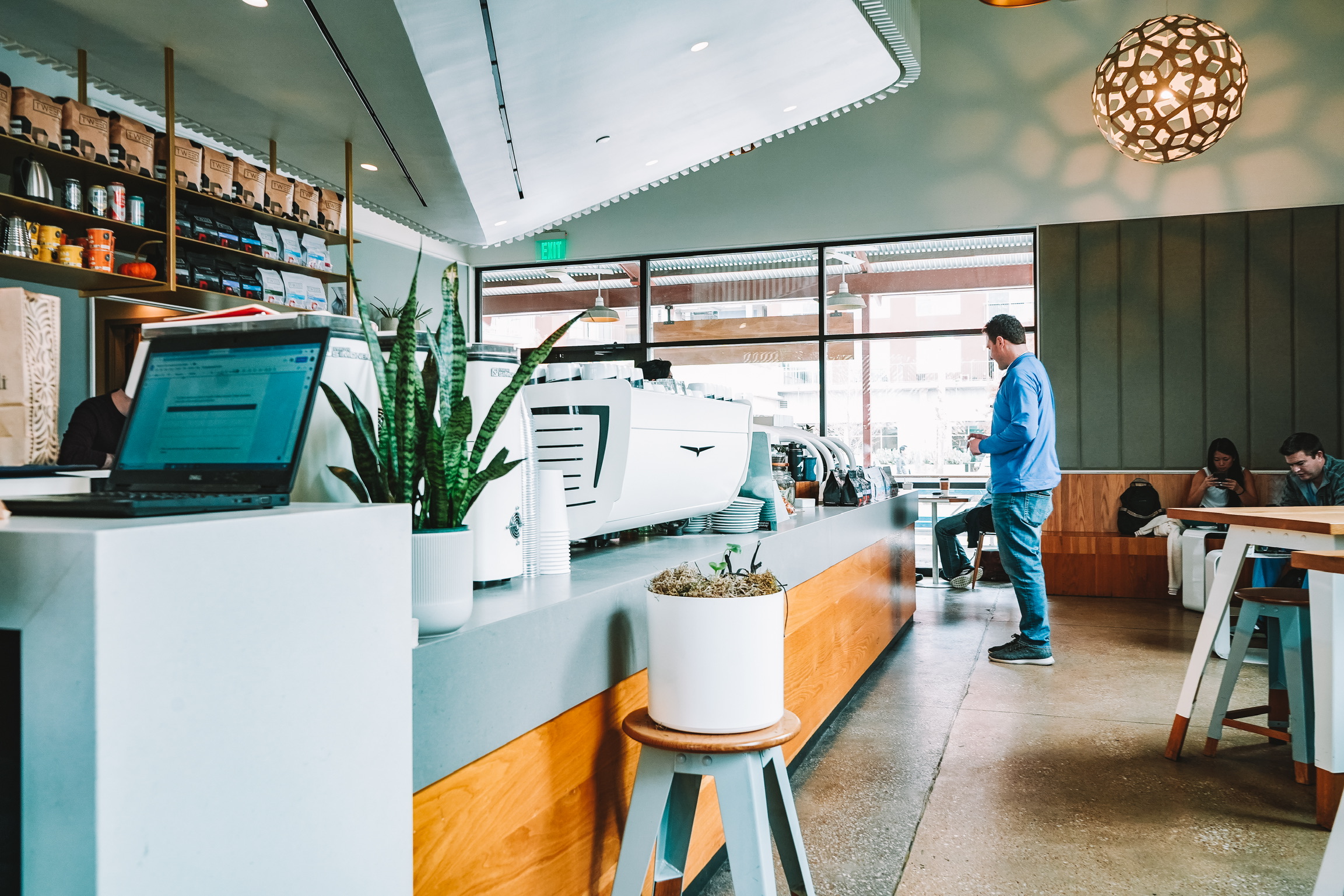 Coffee shop front of bar with customer and open laptop