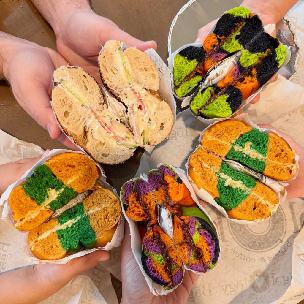 Hands holding Bagelology colorful bagels